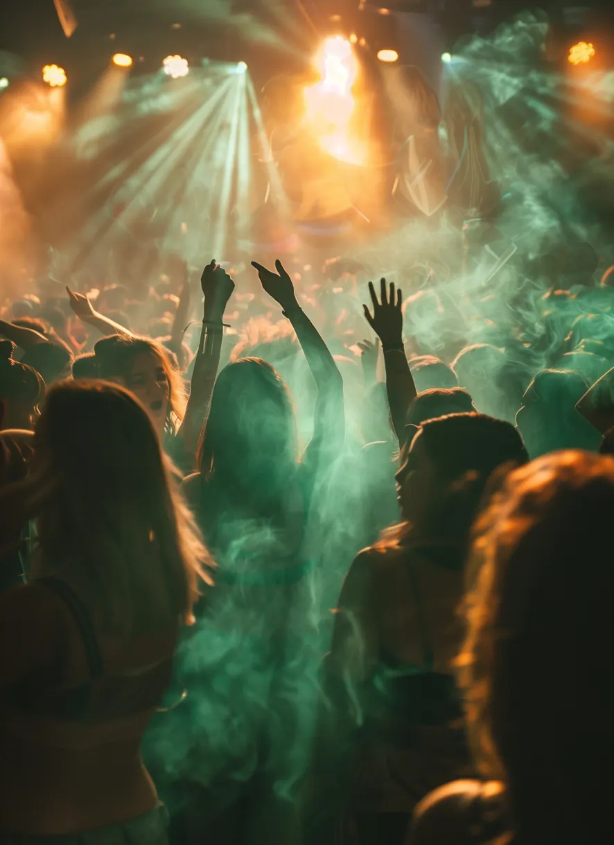 A crowd dancing under green stage lights